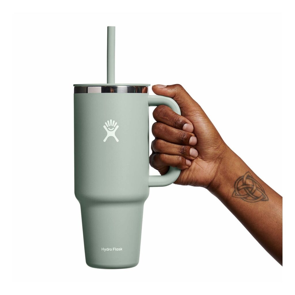 A hand holding a mint green lead-free tumbler from Hydro Flask