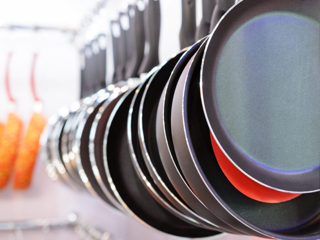 A line of aluminum and steel pans hanging on a rack