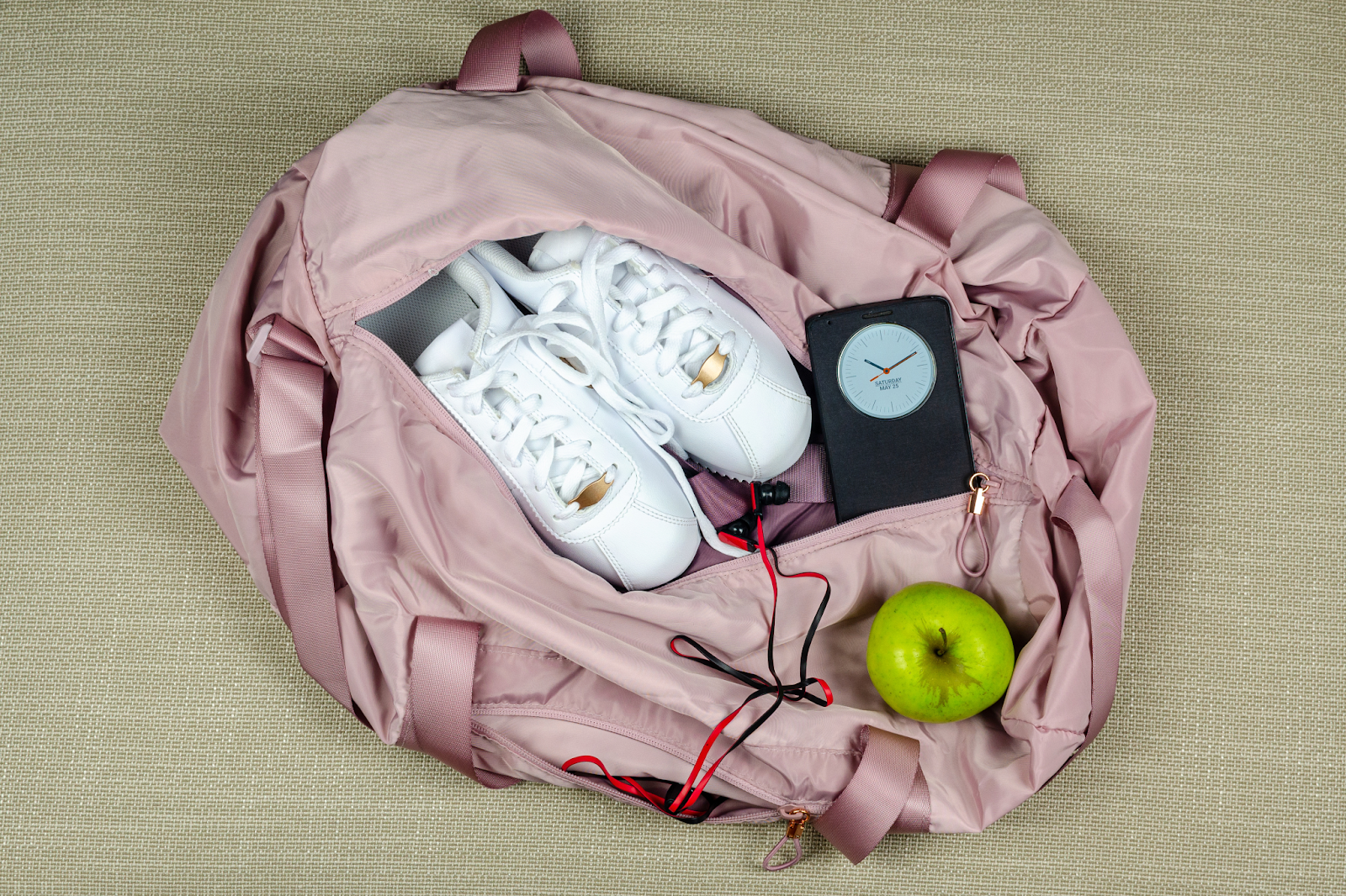 A sustainable gym bag with apples, shoes, and a weight.