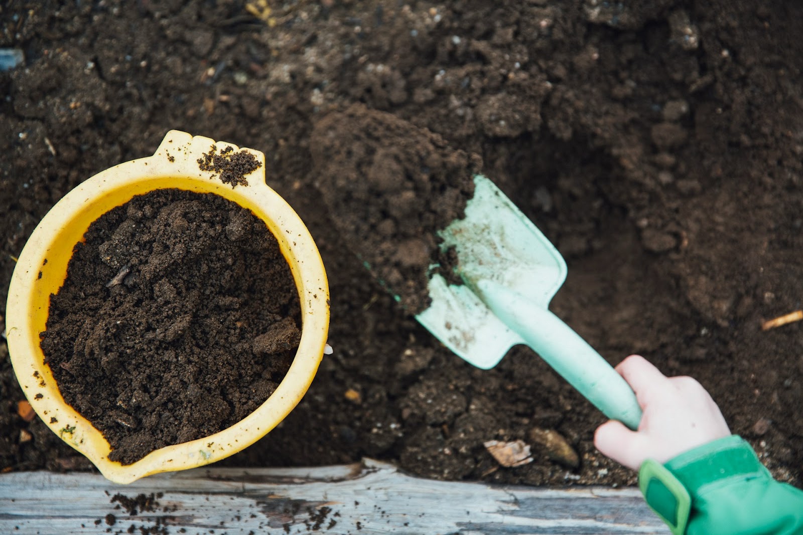 A child shovels a mound of compost and soil into her bucket